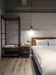 Puremeworld Hotel في تايبيه: غرفة نوم مع سرير كبير و كومودينو مع سرير مزدوج