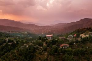 een stad op een heuvel met bergen op de achtergrond bij Mukteshwar Treat Resort in Mukteswar