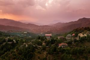 une ville sur une colline avec des montagnes en arrière-plan dans l'établissement Mukteshwar Treat Resort, à Mukteswar 25 autres photos