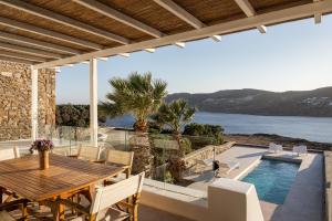un patio con tavolo, sedie e piscina di Villa Hola Mykonos a Mykonos Città