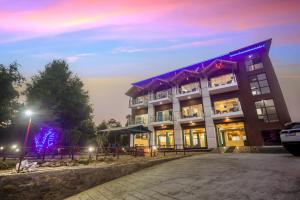 un grand bâtiment avec un panneau bleu devant dans l'établissement Mukteshwar Treat Resort, à Mukteswar