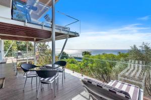 a house with a balcony with a table and chairs at Allure in Point Lookout