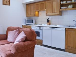 uma cozinha com um sofá, um fogão e um micro-ondas em Grooms Room em Thirlmere