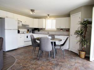 a kitchen with white cabinets and a table and chairs at Paradise Canyon Golf Resort, Signature Walkout Condo 382 in Lethbridge