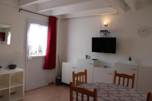 un salon avec une table et une télévision murale dans l'établissement Agréable maison de vacances, à Gallargues-le-Montueux