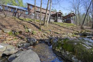 une maison sur une colline avec un ruisseau devant elle dans l'établissement Indian Springs Lodge, à Broken Bow