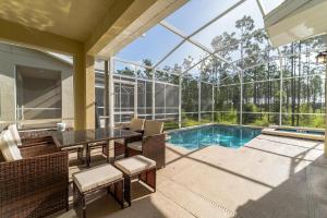 a patio with a table and chairs next to a swimming pool at Ruby Falls Villa in Kissimmee