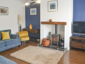 a living room with a fireplace and a tv at Tern House in Amble