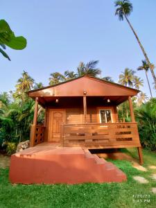 a small building with a bench in the grass at Tranquil Beach Resort in Harihareshwar
