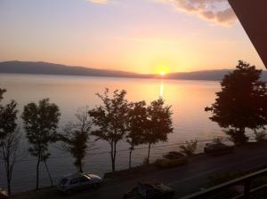 a sunset over a body of water with cars parked at Guest House Lokoski in Peštani