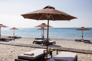 a group of umbrellas and lounge chairs on a beach at Doryssa Coast Apartments in Pythagoreio