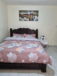 a bed with a pink comforter with flowers on it at Lux Suites Donholm Family Bungalow in Nairobi