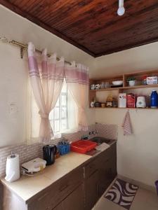 a kitchen with a sink and a window with curtains at Lux Suites Donholm Family Bungalow in Nairobi