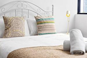 ein Schlafzimmer mit einem weißen Bett mit Kissen in der Unterkunft Four bedroom apartment with facilities in Olympic Park in Sydney
