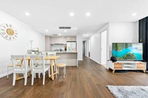 a living room with a dining table and a kitchen at Four bedroom apartment with facilities in Olympic Park in Sydney