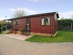 a small wooden cabin with a brick patio at Mallard Lodge in Gorleston-on-Sea