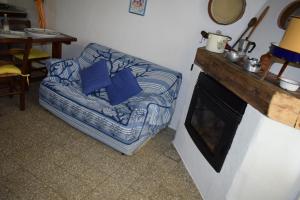 a couch with blue pillows sitting next to a fireplace at Sa Domitta di Suiles in Olbia