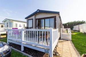 a tiny house with a white fence and a porch at Superb 8 Berth Dog Friendly Caravan At Haven Caister In Norfolk Ref 30009d in Great Yarmouth