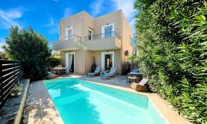 a villa with a swimming pool in front of a house at Apple Villas in Mouríon