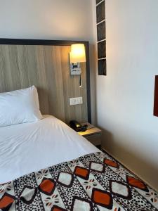 um quarto com uma cama, um candeeiro e um telefone em ONOMO Hotel Lomé em Lomé