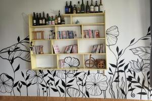 a shelf with wine bottles and books on a wall at Books Home Dalat in Da Lat