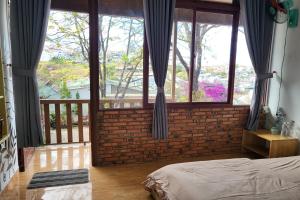 a bedroom with a large window and a brick wall at Books Home Dalat in Da Lat