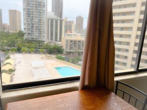a window with a view of a pool in a city at Hawaiian Monarch 1105 condo in Honolulu