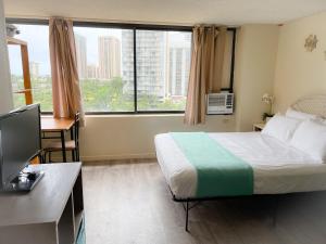 a hotel room with a bed and a desk and a window at Hawaiian Monarch 1105 condo in Honolulu