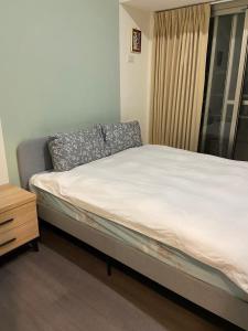 Bett in einem Zimmer mit Fenster und Kissen in der Unterkunft 果芒驛站旅店 in Taipeh