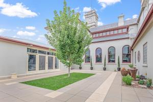 a tree in the courtyard of a building with a clock tower at Clocktower Suites in Echuca