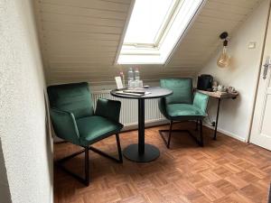 a room with a table and two green chairs at Bed and Breakfast Goes in Goes