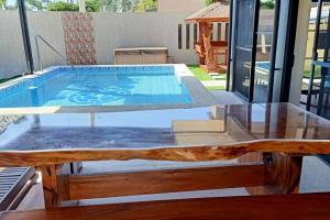 a pool with a wooden table and a tableasteryasteryasteryasteryasteryasteryastery at 5BR w/ Covered Pool, Jacuzzi, & Gazebo 
