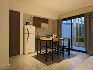 cocina con nevera, mesa y sillas en Hedonism apartments en Mar del Plata