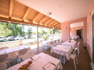 ein Restaurant mit weißen Tischen und Stühlen und großen Fenstern in der Unterkunft Pomposa Residence in Lido di Pomposa