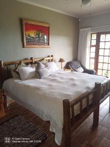 a bedroom with a large bed with white sheets and pillows at Leopards and Louries Bush Lodge in Camperdown