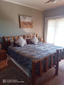 a bedroom with a large bed with a wooden frame at Leopards and Louries Bush Lodge in Camperdown