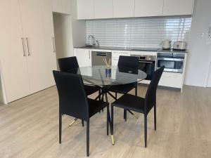 a kitchen with a glass table and black chairs at Cityscape in Christchurch