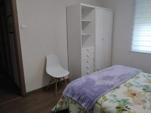 a bedroom with a bed and a white chair at Apartamento Casco Antiguo Ponferrada in Ponferrada