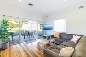 una sala de estar con un sofá y una mesa en Tomaree Cottage 12 Tomaree Road - 200 mtrs to Beach - Pet Friendly, linen, WiFi & aircon, en Shoal Bay