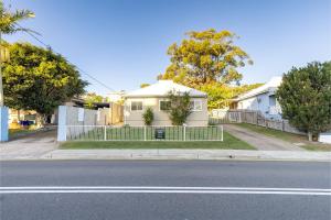 una casa blanca con una valla en una calle en Tomaree Cottage 12 Tomaree Road - 200 mtrs to Beach - Pet Friendly, linen, WiFi & aircon, en Shoal Bay