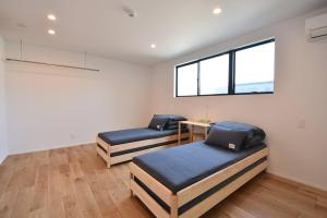 two beds in a room with a window at Enzo Ikeda A in Omura