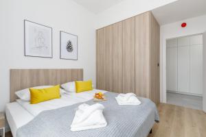 a bedroom with a bed with yellow and white towels at Shellter Premium Apartment Beachside by Renters Prestige in Rogowo