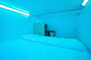 Bobopod Kota Tua, Jakarta في جاكرتا: سرير في غرفة مع أضواء زرقاء