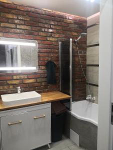 y baño con pared de ladrillo, lavabo y bañera. en IGO-Apartament- 2 sypialnie i Salon, en Suwałki