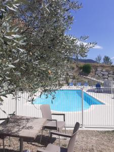 a table and chairs next to a swimming pool at L'Oliveraie in Nyons