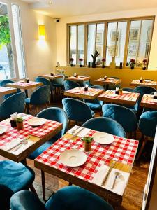 un restaurante con mesas de madera y sillas azules en Hotel Douglas, en Puteaux
