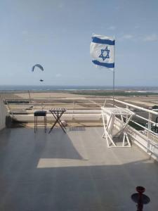 a flag on the top of a cruise ship with a table and a chair at דירה נעימה בקומה 11 בזכרון יעקב, מרפסת משקיפה לים in Zikhron Ya‘aqov