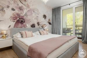 コウォブジェクにあるApartments M&M Kołobrzeg Polankiの花柄の壁紙を用いたベッドルーム1室(大型ベッド1台付)