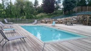 a swimming pool with chairs and a table on a wooden deck at LOU CHASTEL, DEMEURE PERIGOURDINE CLIMATISEE avec PISCINE PRIVEE et CHAUFFEE in La Bachellerie