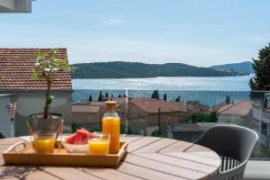 una mesa con una bandeja de zumo y un bol de fruta en Villa Kuzmanić, en Trogir